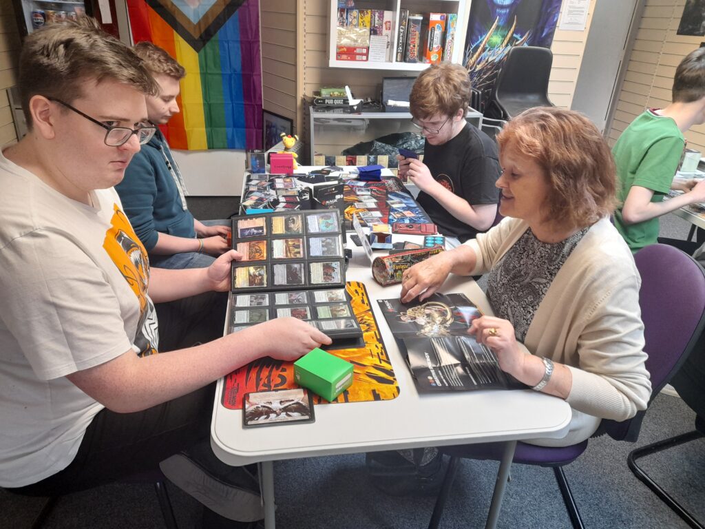 Josh and Lennon playing Magic the Gathering with James teaching Trish how the game is played.