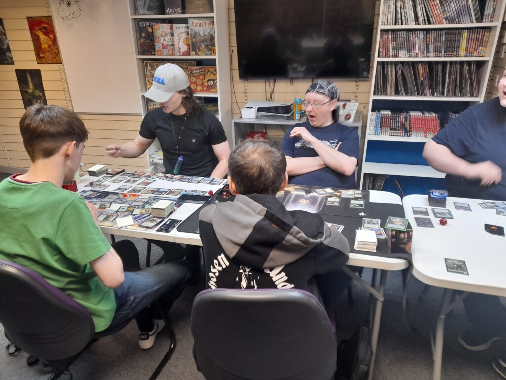 Five players playing Magic the Gathering with Commander decks